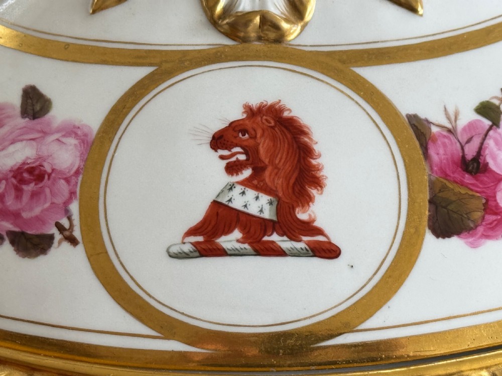 An oval Regency Worcester porcelain entree dish with a fitted lid, featuring hand-painted pink rose garlands, gilt gadrooned rims, twin gilded handles, a heraldic lion crest, and a gold leaf-and-pineapple finial. View V