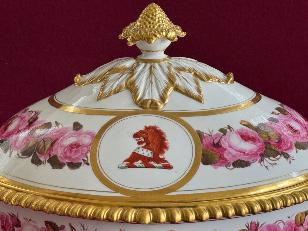 An oval Regency Worcester porcelain entree dish with a fitted lid, featuring hand-painted pink rose garlands, gilt gadrooned rims, twin gilded handles, a heraldic lion crest, and a gold leaf-and-pineapple finial. View VI