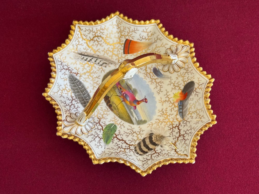 A Regency Flight, Barr and Barr Worcester porcelain basket featuring hand-painted feathers, a central landscape with a bird, and gold seaweed gilding on a white background with a central handle. View III