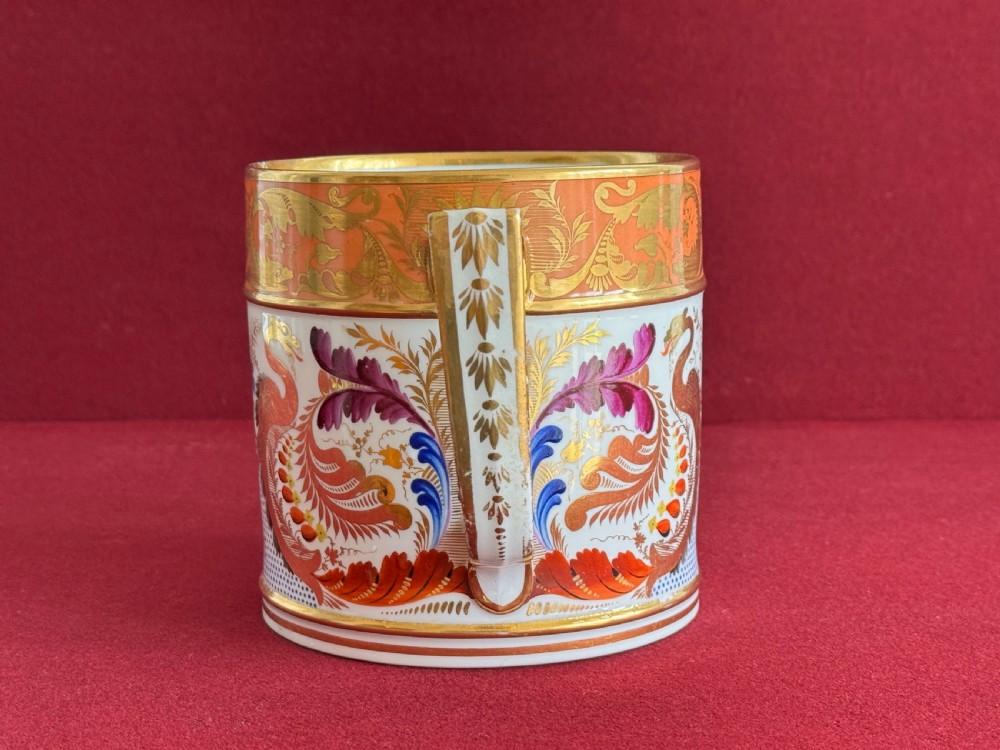 A Regency Derby porcelain porter mug featuring hand painted bird motifs, an orange gilded upper border, and an angular handle. View IV