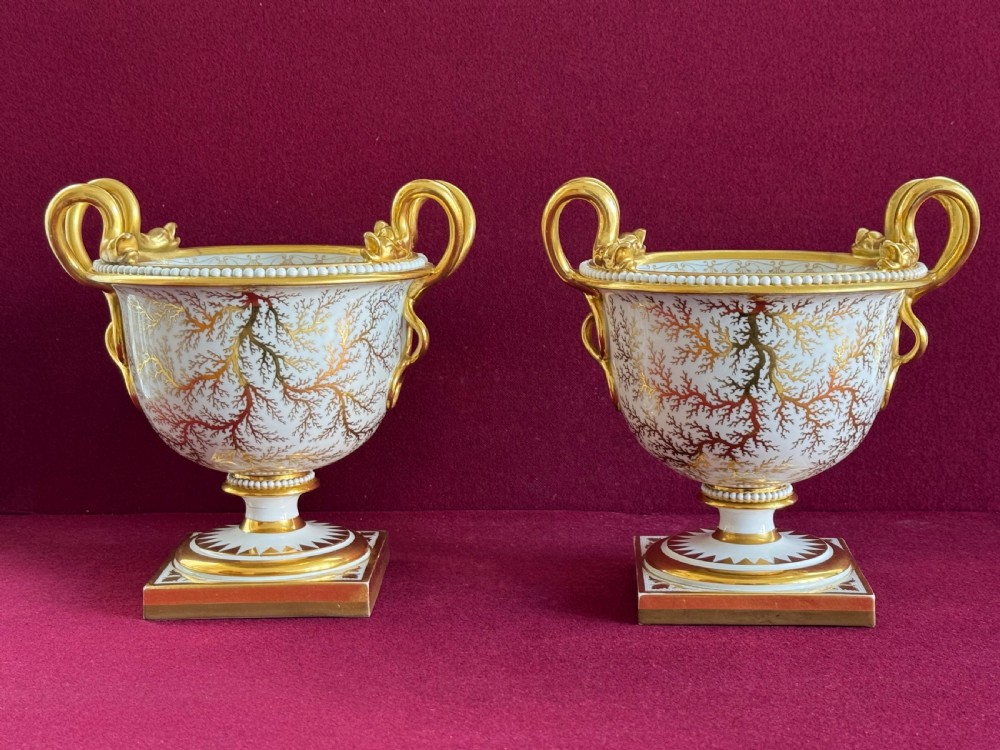 A pair of Regency Flight, Barr and Barr Worcester porcelain urn-shaped vases featuring hand-painted figurative panels, gilded scroll handles, beaded rims, and square plinth bases. View II