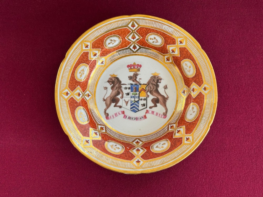 A circular Coalport porcelain soup plate featuring a gilded orange patterned rim and a central hand-painted coat of arms with lion supporters.