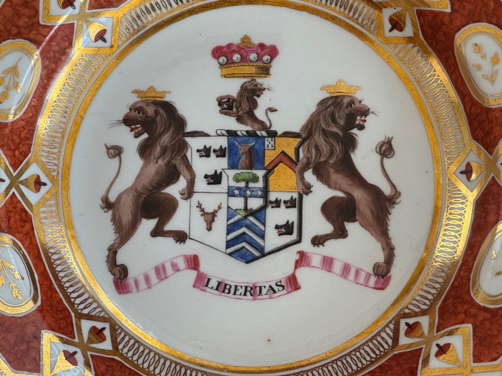 A circular Coalport porcelain soup plate featuring a gilded orange patterned rim and a central hand-painted coat of arms with lion supporters. View II