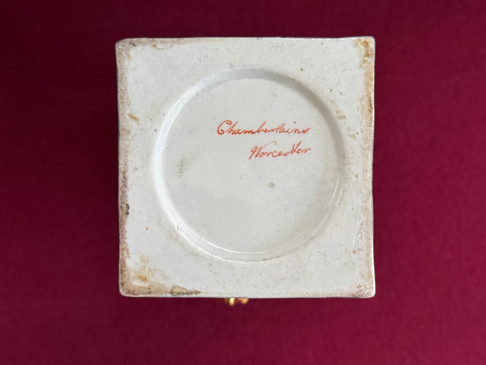 A Regency Chamberlain Worcester porcelain urn-shaped vase with a lid, featuring an orange pattern ground, gilded accents, side mask handles, and a painted feather panel on a square base. View XI