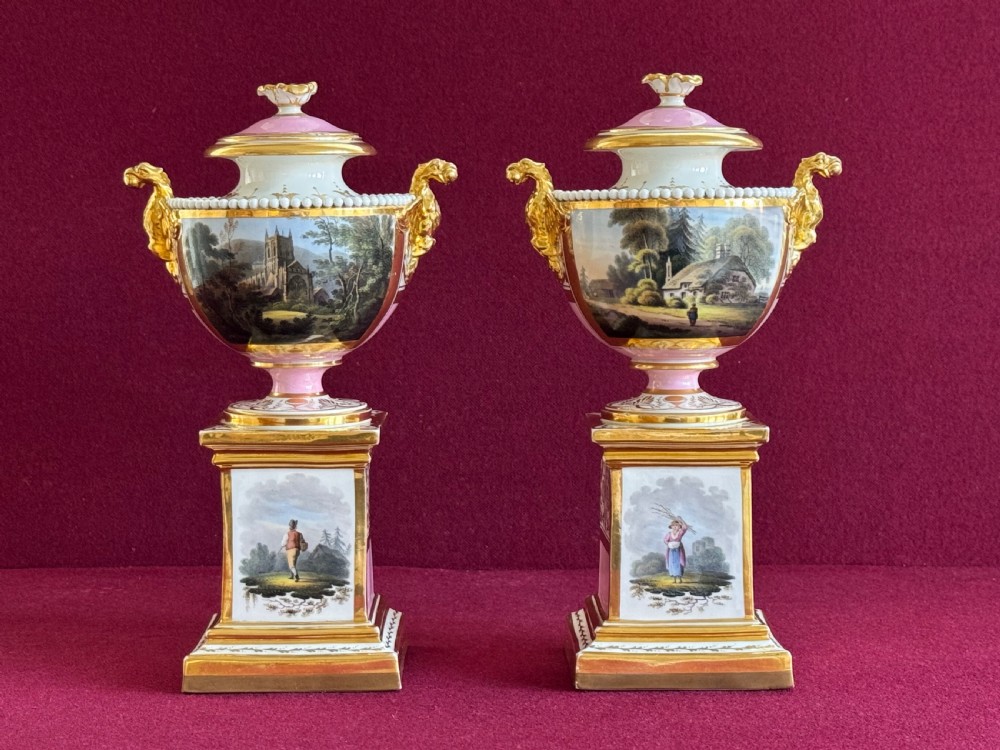 A three-piece Flight, Barr and Barr Worcester porcelain garniture set with hand-painted landscape scenes, pink ground borders, and gilded scroll handles resting on square pedestal bases. View XI
