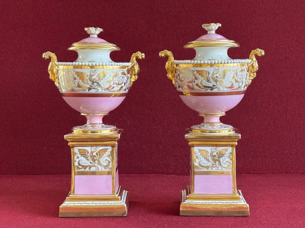 A three-piece Flight, Barr and Barr Worcester porcelain garniture set with hand-painted landscape scenes, pink ground borders, and gilded scroll handles resting on square pedestal bases. View XIII