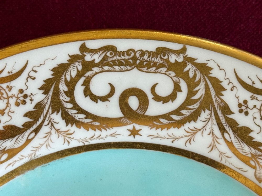 A circular Regency porcelain plate featuring a central hand-painted marine shell motif surrounded by a turquoise ground and gilded scrollwork on a white rim. View IV
