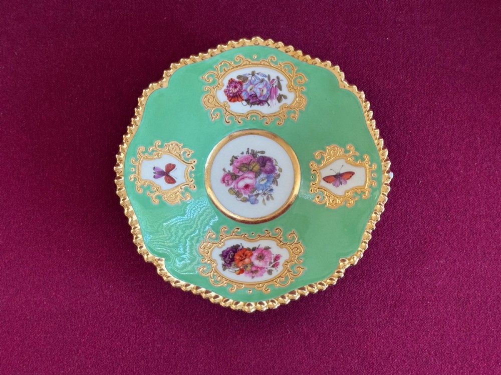 An antique Flight, Barr & Barr porcelain teacup and saucer featuring an apple green ground, hand-painted floral panels, and gilt gadrooned rims. View III