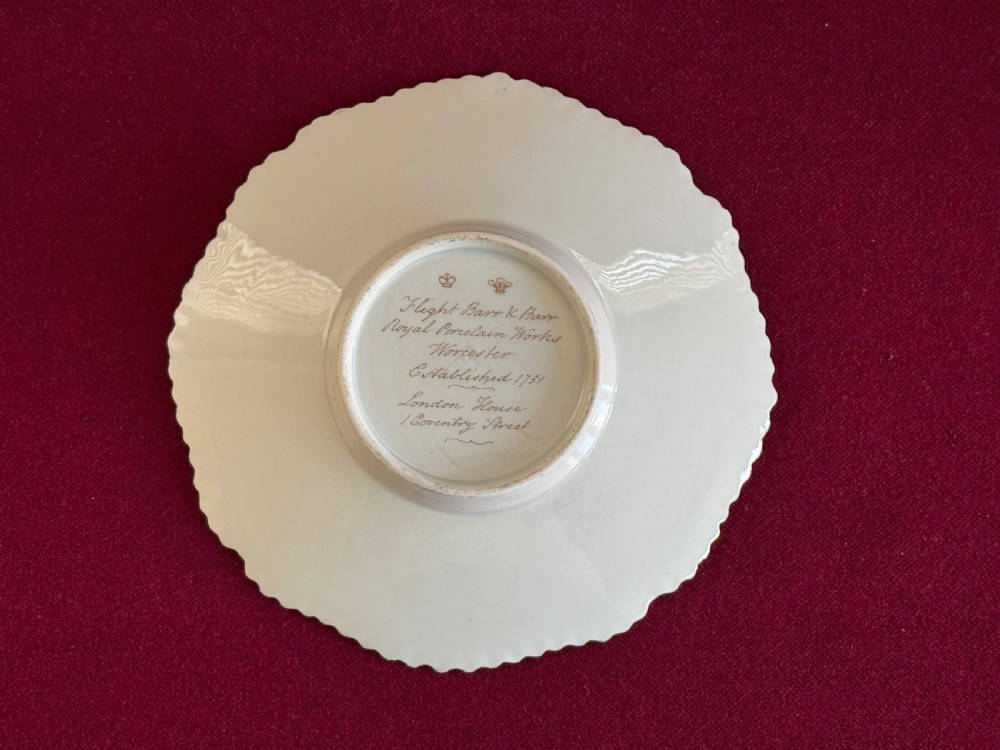 An antique Flight, Barr & Barr porcelain teacup and saucer featuring an apple green ground, hand-painted floral panels, and gilt gadrooned rims. View V