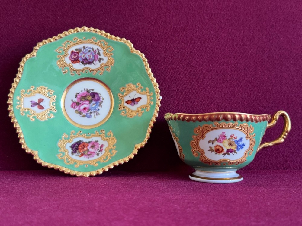 An antique Flight, Barr & Barr porcelain teacup and saucer featuring an apple green ground, hand-painted floral panels, and gilt gadrooned rims. View XI