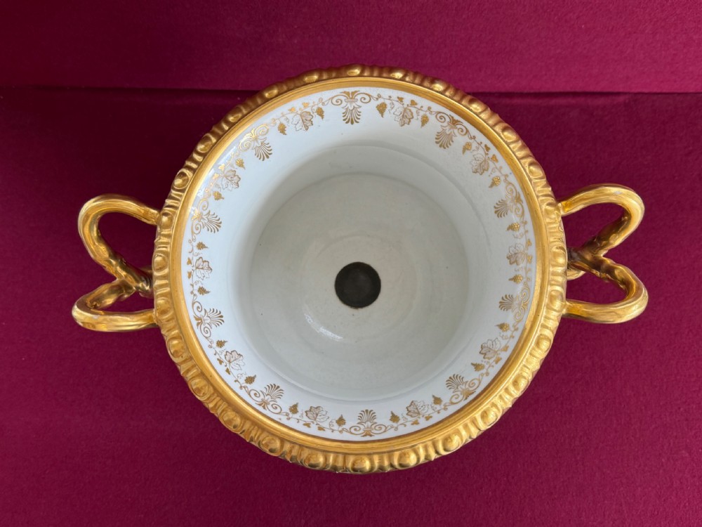 A Regency Flight, Barr and Barr Worcester cobalt blue porcelain Warwick urn featuring twin gilt vine-twisted handles, intricate gilt tooling, and a central hand-painted panel depicting two figures in a landscape. View V