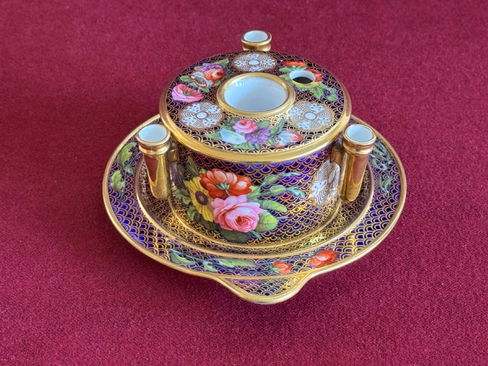 An early 19th-century circular English porcelain inkstand featuring gold scale gilding on a dark blue ground, floral reserves, and three cylindrical quill holders. View II