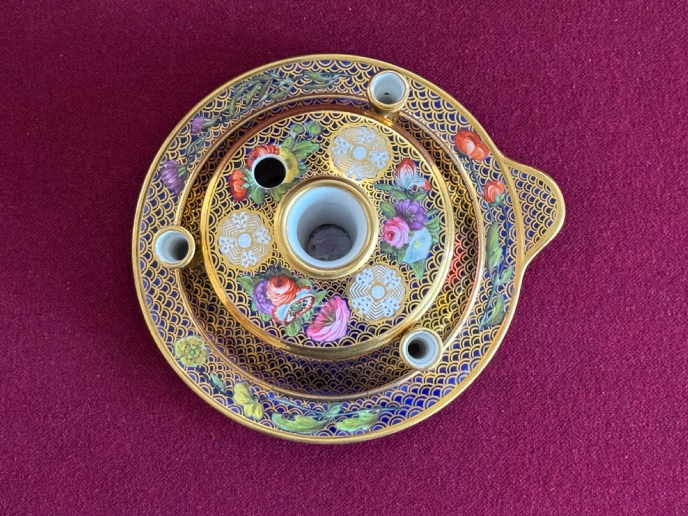 An early 19th-century circular English porcelain inkstand featuring gold scale gilding on a dark blue ground, floral reserves, and three cylindrical quill holders. View V