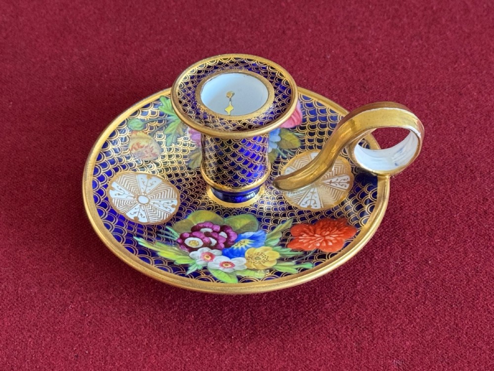 A Regency period Spode porcelain chamber candlestick decorated with a cobalt blue scale pattern, gilt trim, and hand-painted floral panels.