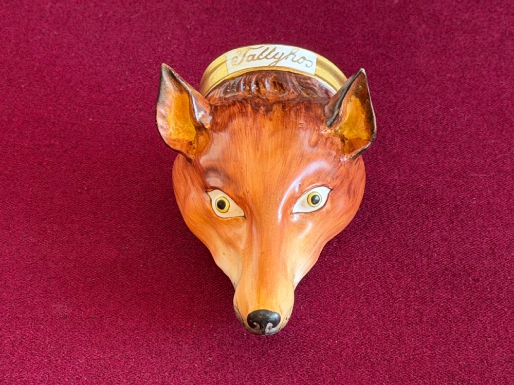 An antique porcelain stirrup cup moulded in the form of a fox head with hand-painted details and a gilded rim inscribed with Tallyho.