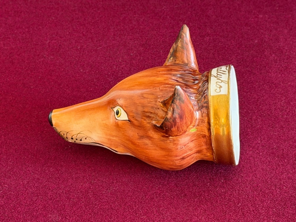 An antique porcelain stirrup cup moulded in the form of a fox head with hand-painted details and a gilded rim inscribed with Tallyho. View III