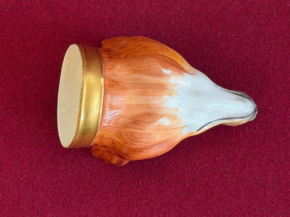 An antique porcelain stirrup cup moulded in the form of a fox head with hand-painted details and a gilded rim inscribed with Tallyho. View V