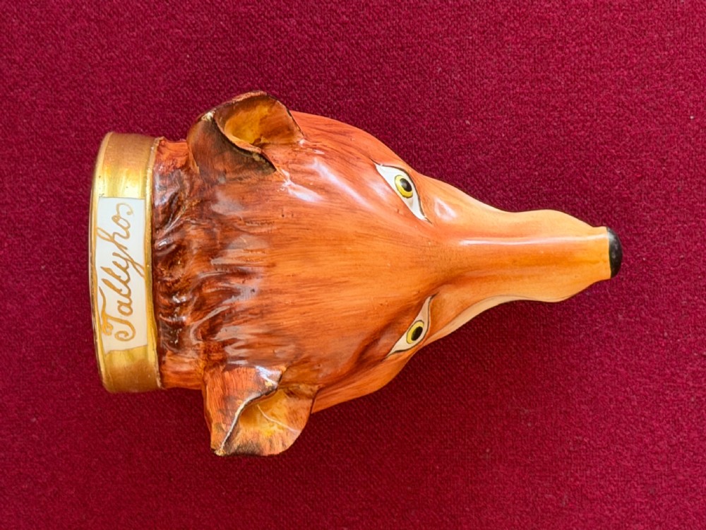 An antique porcelain stirrup cup moulded in the form of a fox head with hand-painted details and a gilded rim inscribed with Tallyho. View VII