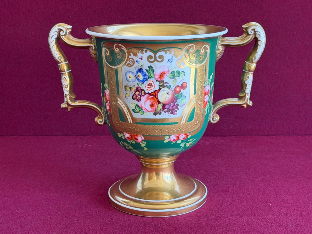 A two-handled green porcelain cup decorated with gold gilding and a hand-painted fruit and floral cartouche on a pedestal foot. View II