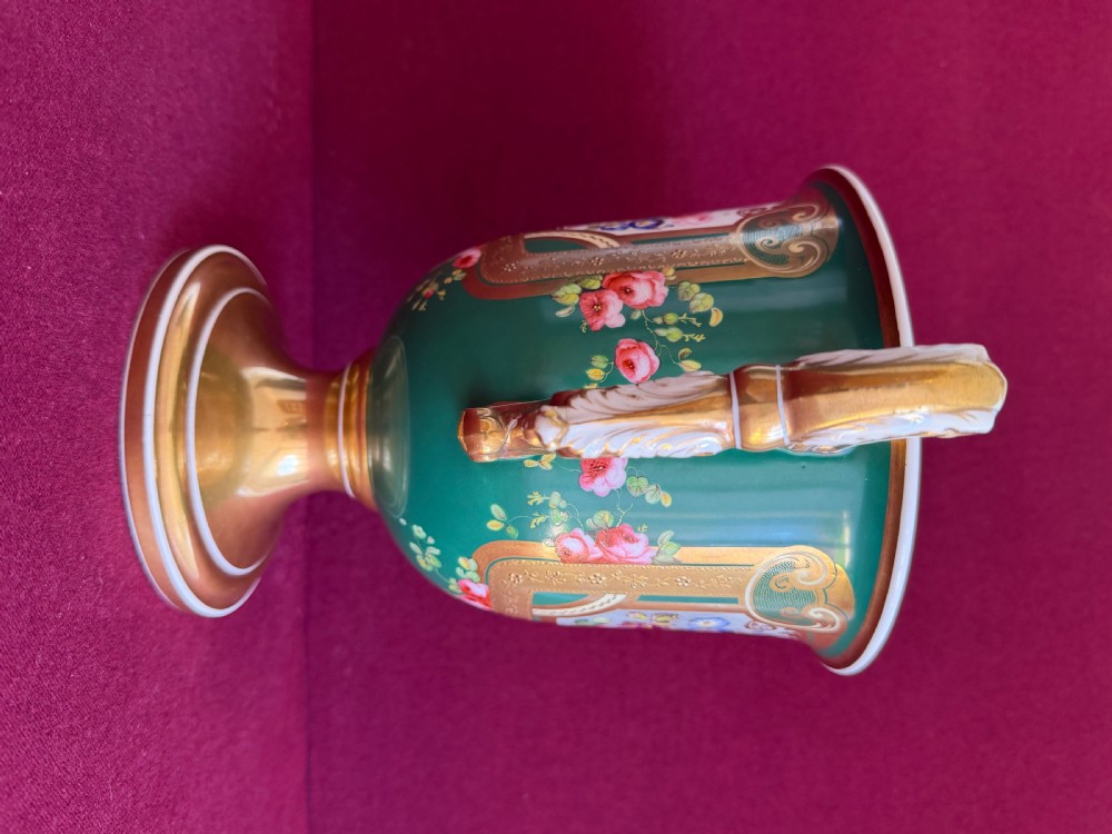 A two-handled green porcelain cup decorated with gold gilding and a hand-painted fruit and floral cartouche on a pedestal foot. View III