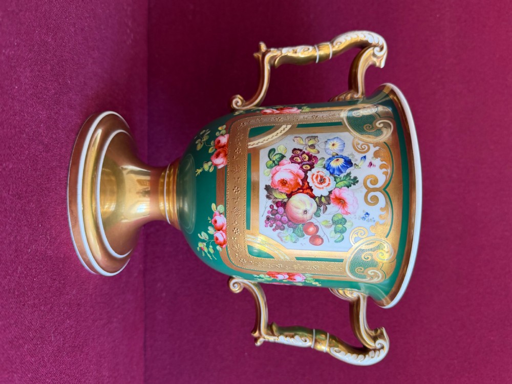 A two-handled green porcelain cup decorated with gold gilding and a hand-painted fruit and floral cartouche on a pedestal foot. View VI