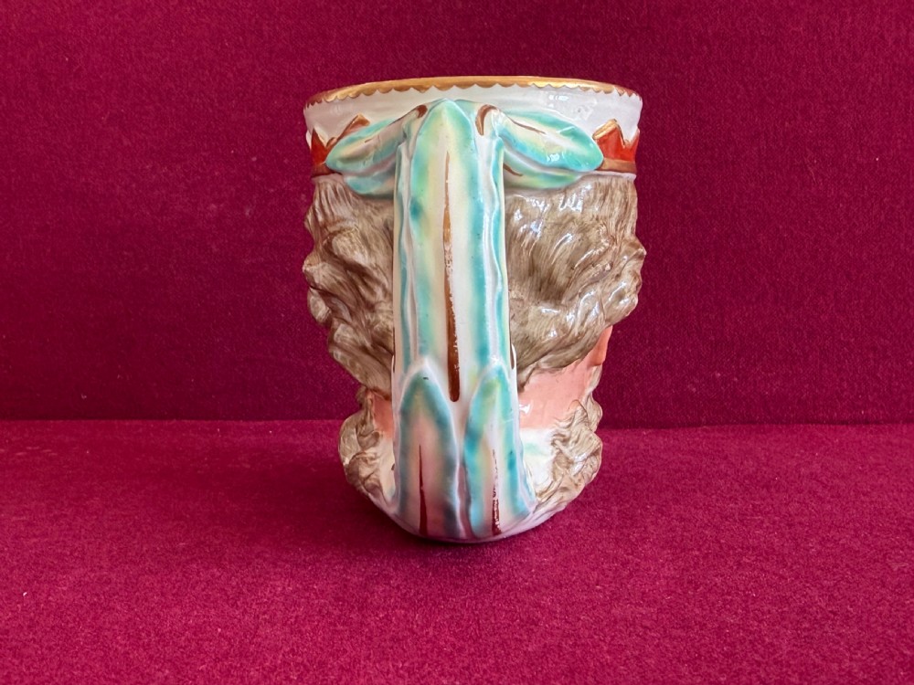An 18th-century Derby porcelain mug sculpted in the shape of Neptunes head with a painted beard, skin tones, and a red and gold crown rim. View III