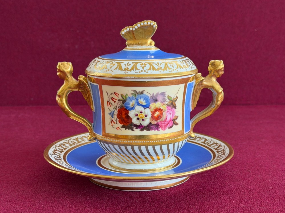 An antique Regency porcelain chocolate cup, cover, and saucer decorated with cobalt blue panels, rich gilding, winged caryatid handles, and a central hand-painted floral bouquet. View III