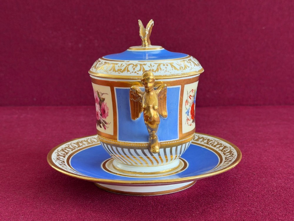 An antique Regency porcelain chocolate cup, cover, and saucer decorated with cobalt blue panels, rich gilding, winged caryatid handles, and a central hand-painted floral bouquet. View IV