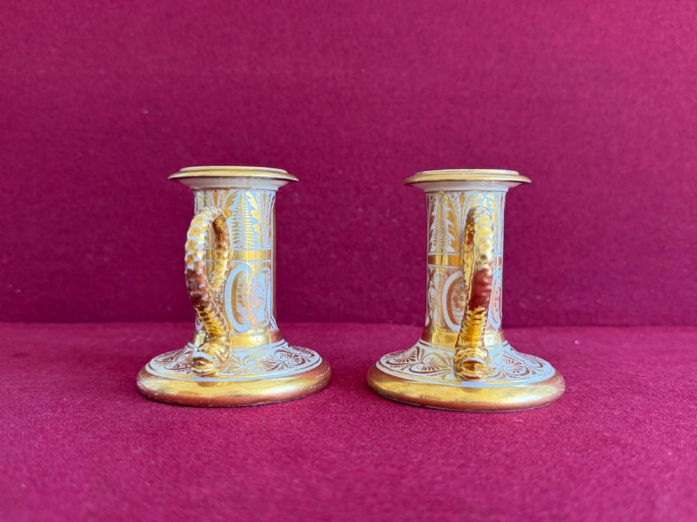 A pair of early nineteenth-century porcelain candlesticks featuring hand-painted landscape scenes on the shafts and detailed gilding on the bases. View IV