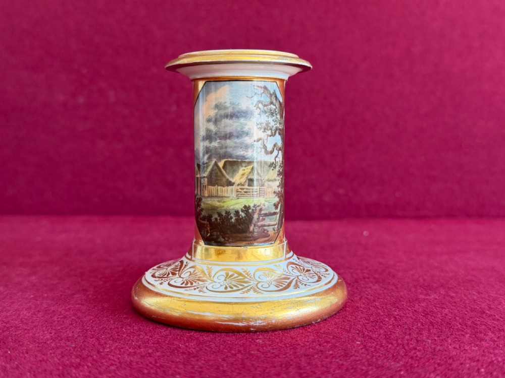 A pair of early nineteenth-century porcelain candlesticks featuring hand-painted landscape scenes on the shafts and detailed gilding on the bases. View VI
