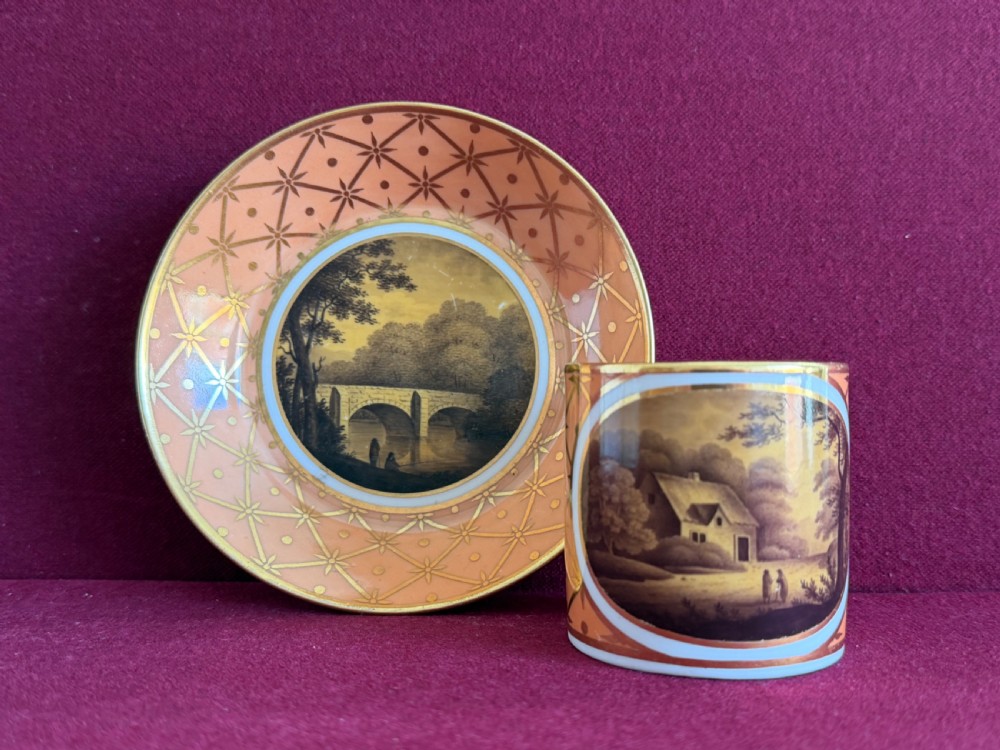 A Georgian Flight and Barr Worcester porcelain coffee can and saucer with hand-painted sepia landscape vignettes and gilt star patterning on a peach border.