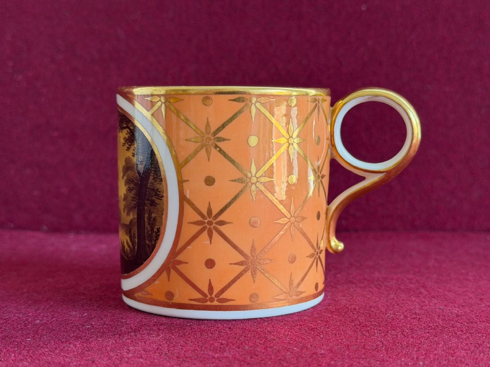 A Georgian Flight and Barr Worcester porcelain coffee can and saucer with hand-painted sepia landscape vignettes and gilt star patterning on a peach border. View VII