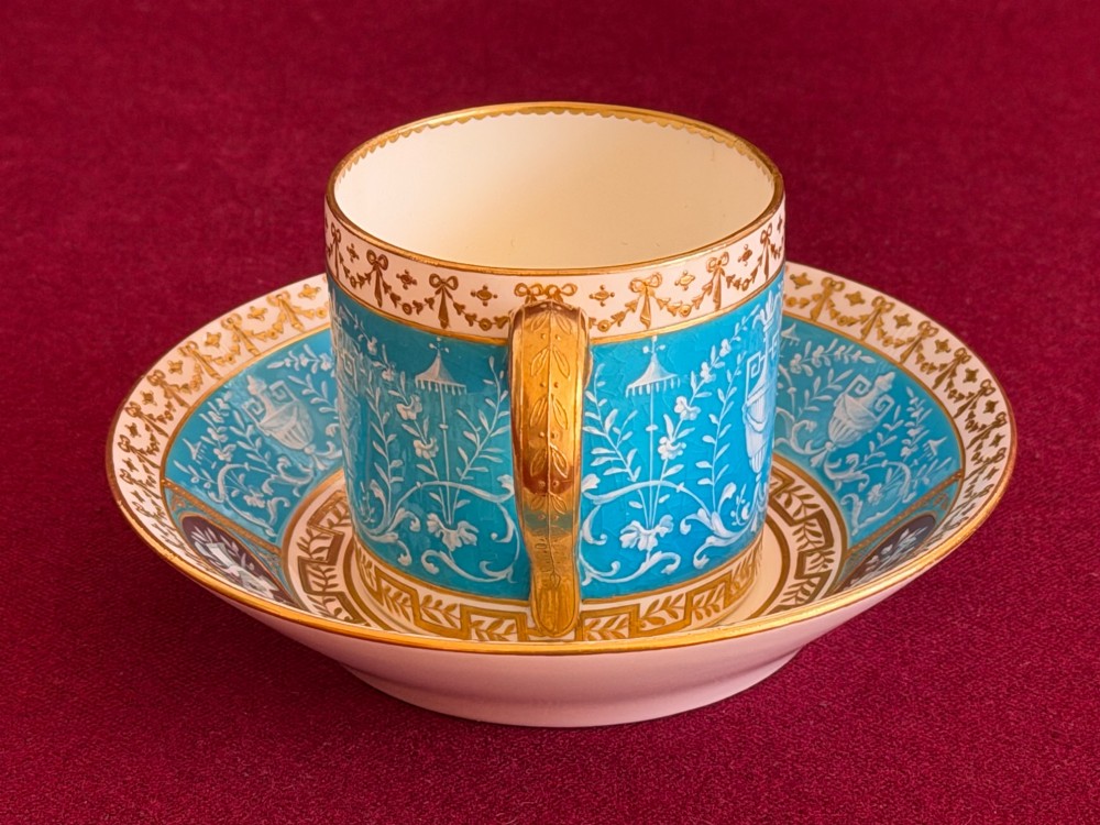 A Victorian Minton porcelain coffee can and saucer decorated with rich turquoise enamel, Neoclassical motifs, classical figure cameos, and gold leaf gilding. View IV