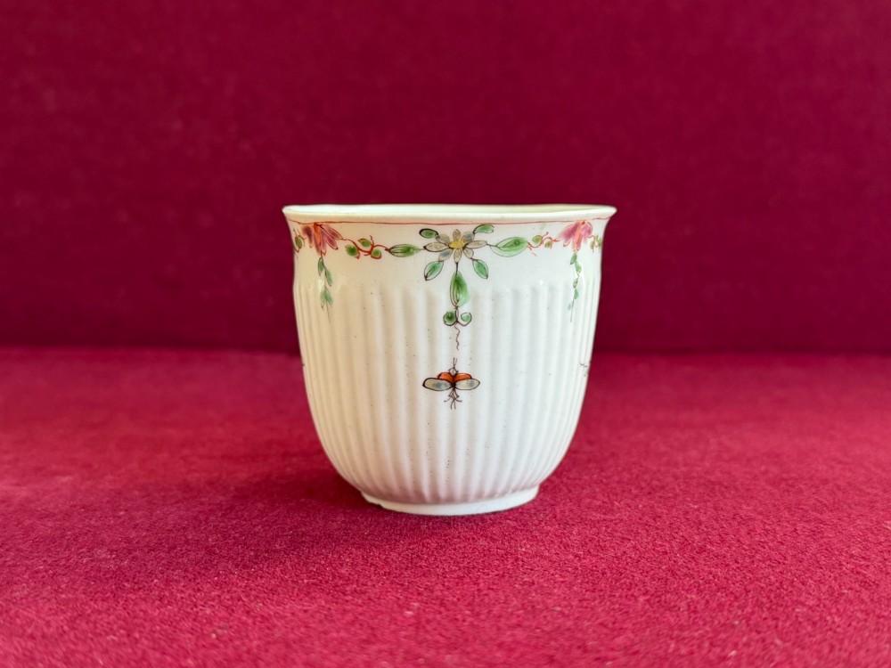 A mid-18th-century white soft-paste porcelain coffee cup featuring vertical reeding, a Rococo scroll handle, and hand-painted floral sprigs. View II