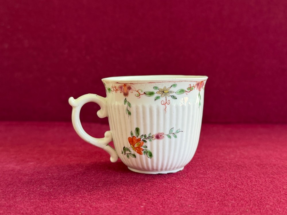 A mid-18th-century white soft-paste porcelain coffee cup featuring vertical reeding, a Rococo scroll handle, and hand-painted floral sprigs. View III