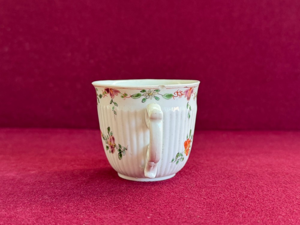 A mid-18th-century white soft-paste porcelain coffee cup featuring vertical reeding, a Rococo scroll handle, and hand-painted floral sprigs. View IV