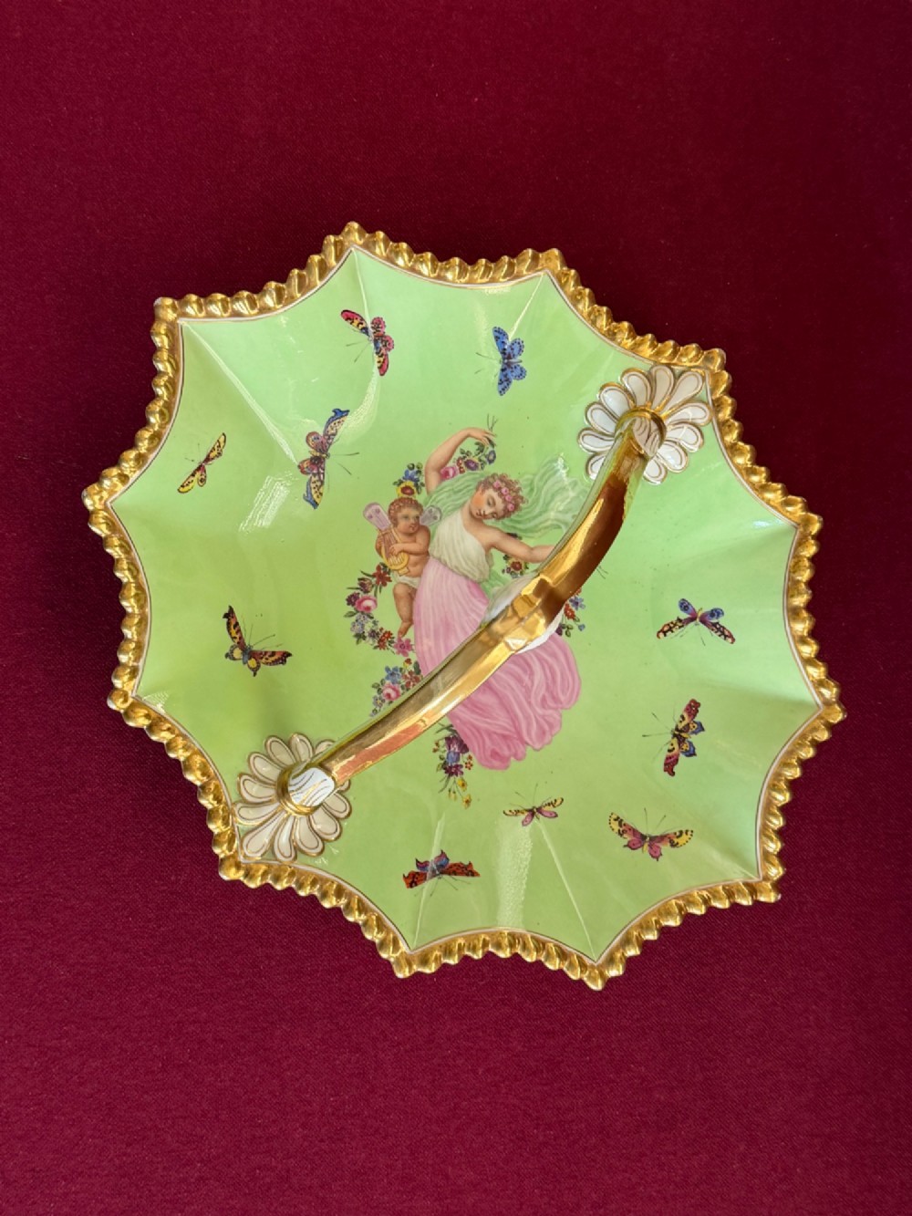 An apple green lobed porcelain basket with a gold overhead handle, gadrooned gilded border, and hand-painted central vignette of a classical figure and butterflies. View III