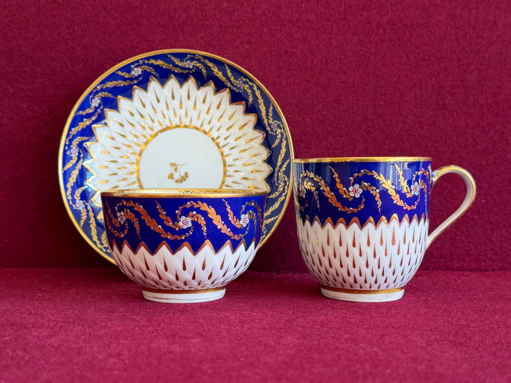 An eighteenth-century Chelsea Derby porcelain trio comprising a coffee cup, tea bowl, and saucer decorated in cobalt blue and gold leaf pattern 34.