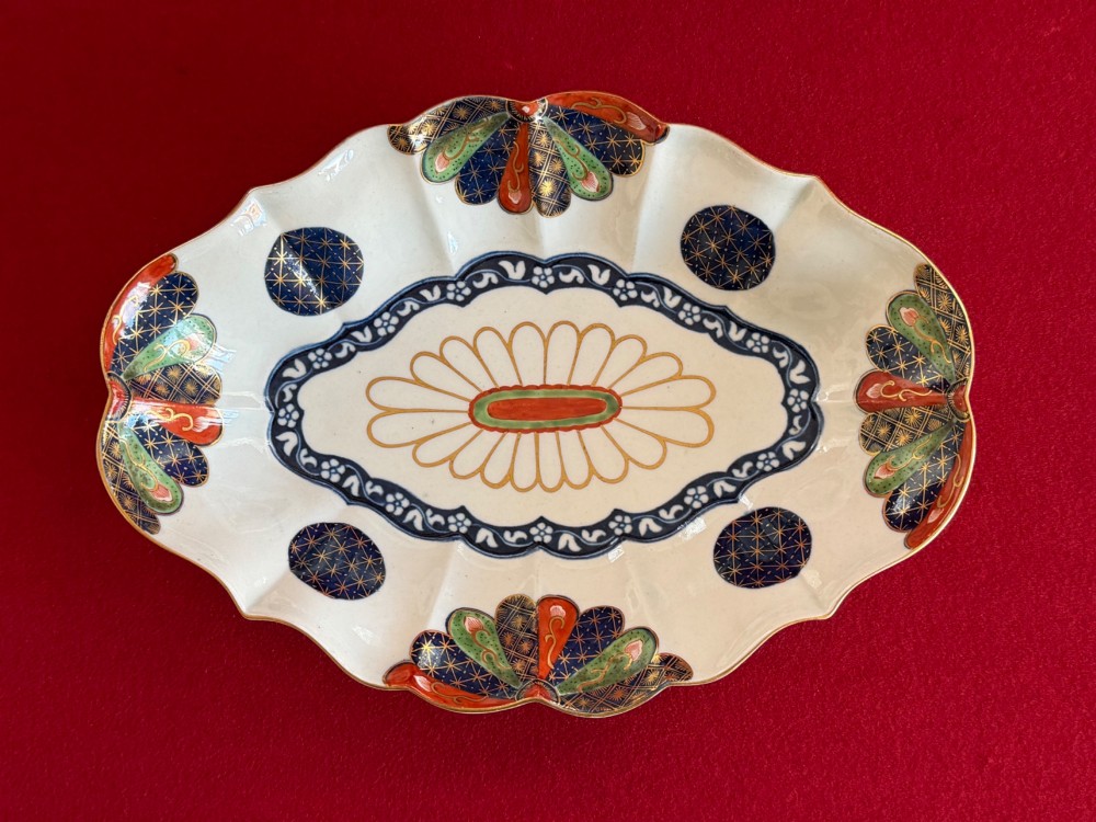An 18th-century oval scalloped soft-paste porcelain dessert dish featuring hand-painted Japanese fan motifs in cobalt blue, iron red, green, and gilding.