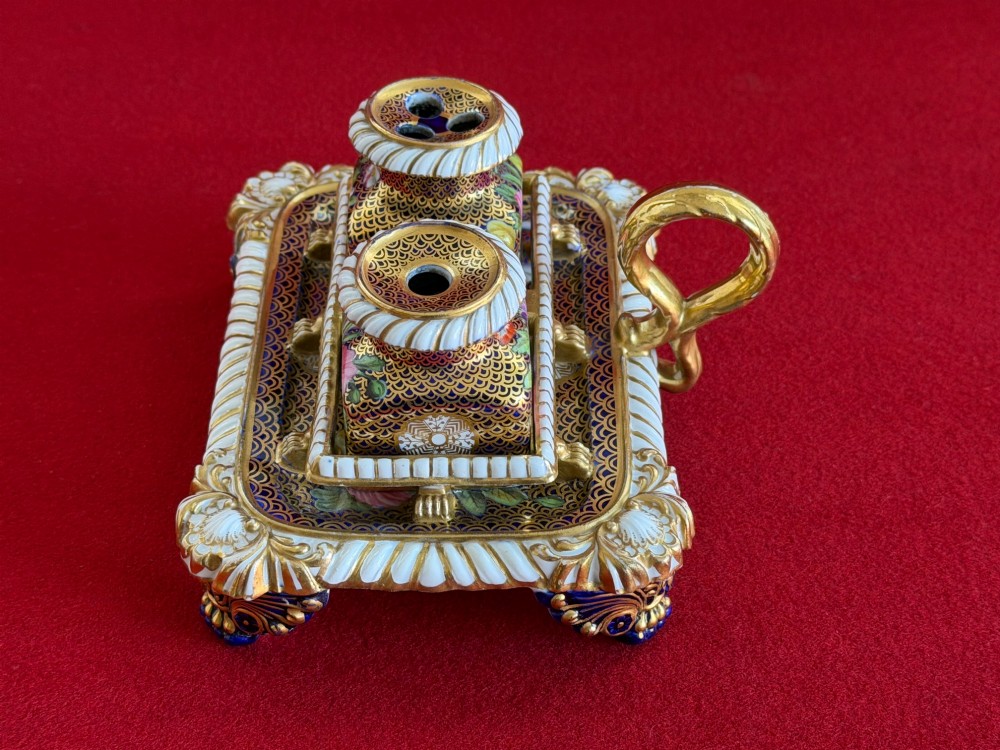 A Regency porcelain inkstand featuring elaborate gilding over a dark blue ground with polychrome floral panels and a central handle. View IV
