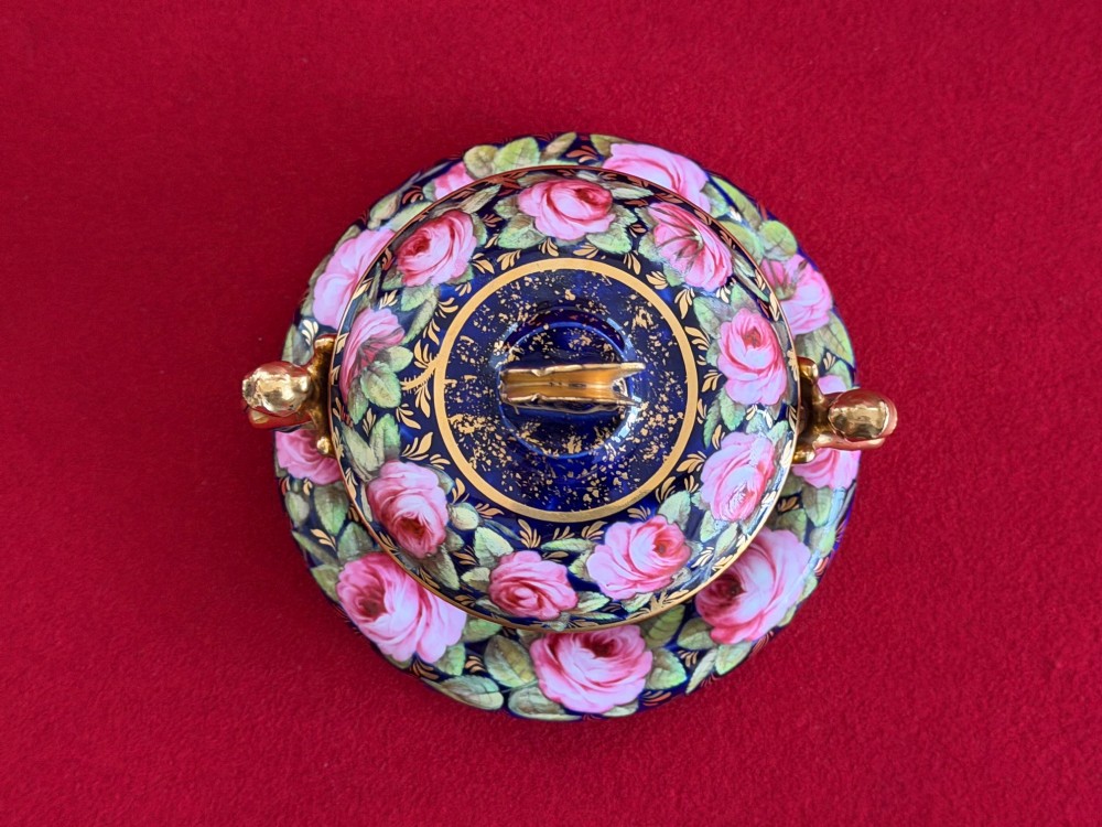 An antique Regency period porcelain covered chocolate cup with matching saucer, decorated in cobalt blue and hand-painted pink roses with winged figure handles and a butterfly finial. View IV