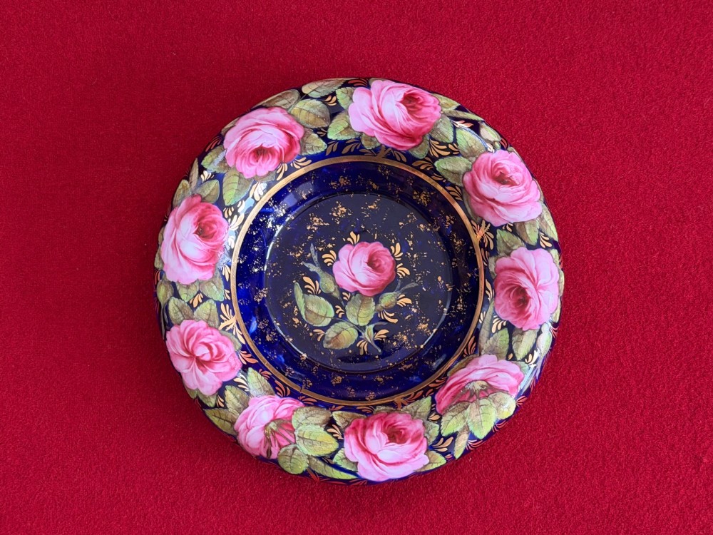 An antique Regency period porcelain covered chocolate cup with matching saucer, decorated in cobalt blue and hand-painted pink roses with winged figure handles and a butterfly finial. View VI