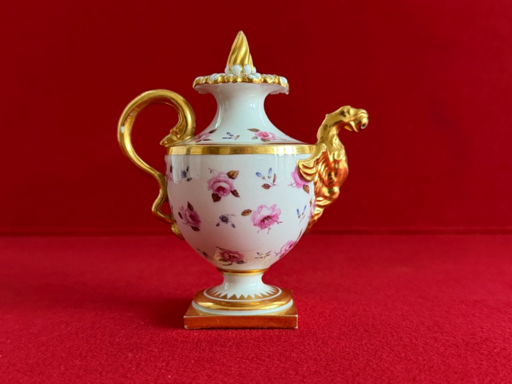 A Regency porcelain rose water sprinkler decorated with pink painted floral sprigs, a gilded spout, a scroll handle, and a square gilded plinth base. View III