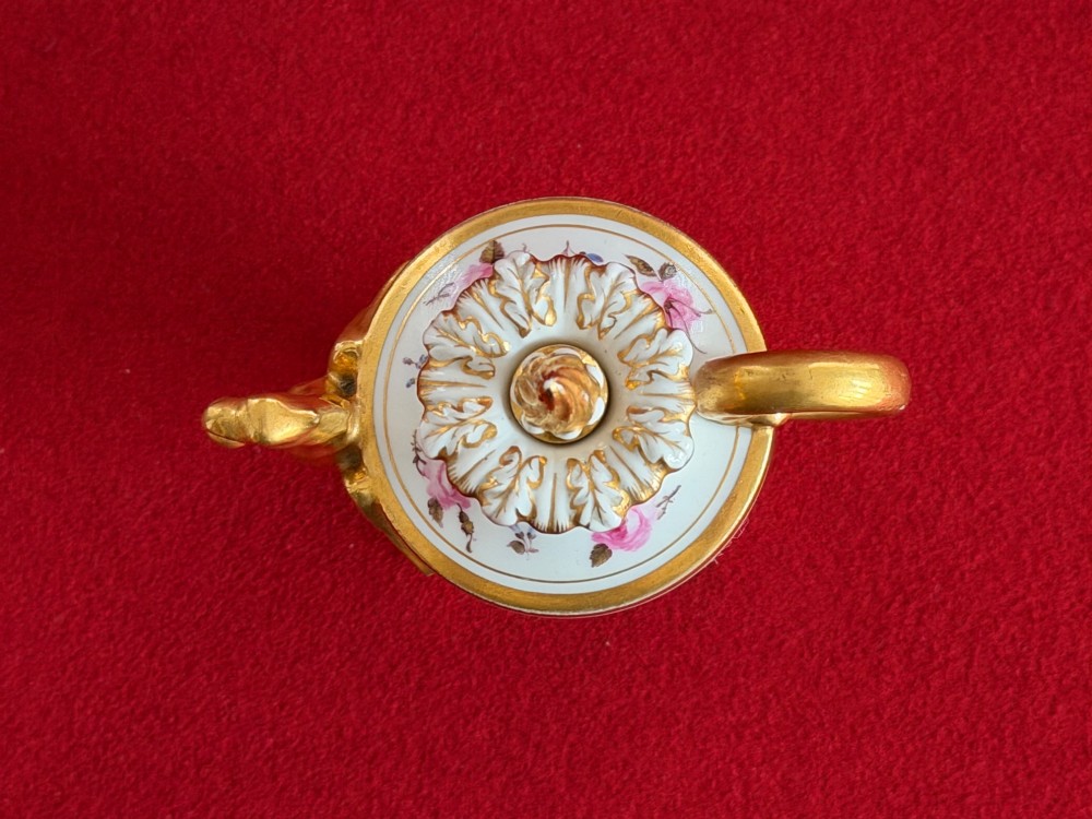A Regency porcelain rose water sprinkler decorated with pink painted floral sprigs, a gilded spout, a scroll handle, and a square gilded plinth base. View VI