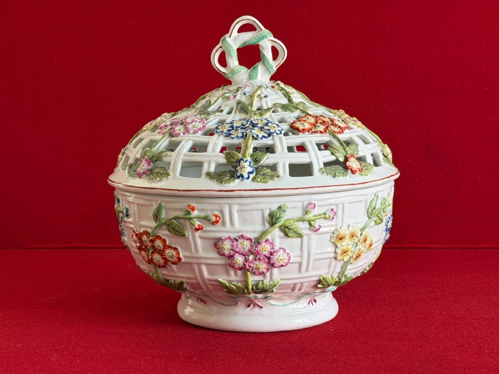 An 18th-century white soft-paste porcelain chestnut basket and domed cover featuring pierced lattice work, hand-applied colourful flowers, green leaves, and a twisted ribbon knop.