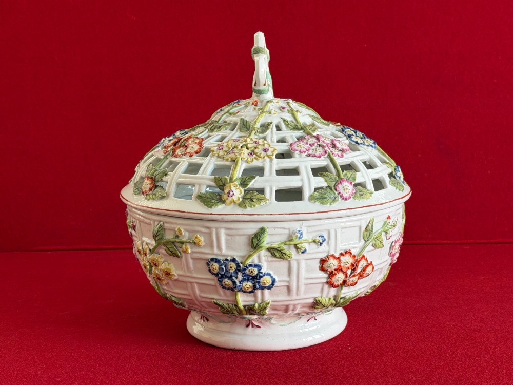 An 18th-century white soft-paste porcelain chestnut basket and domed cover featuring pierced lattice work, hand-applied colourful flowers, green leaves, and a twisted ribbon knop. View IV