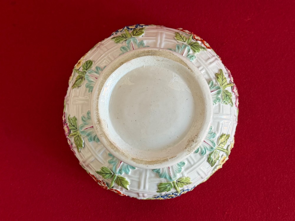 An 18th-century white soft-paste porcelain chestnut basket and domed cover featuring pierced lattice work, hand-applied colourful flowers, green leaves, and a twisted ribbon knop. View V