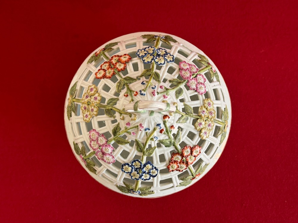 An 18th-century white soft-paste porcelain chestnut basket and domed cover featuring pierced lattice work, hand-applied colourful flowers, green leaves, and a twisted ribbon knop. View VI