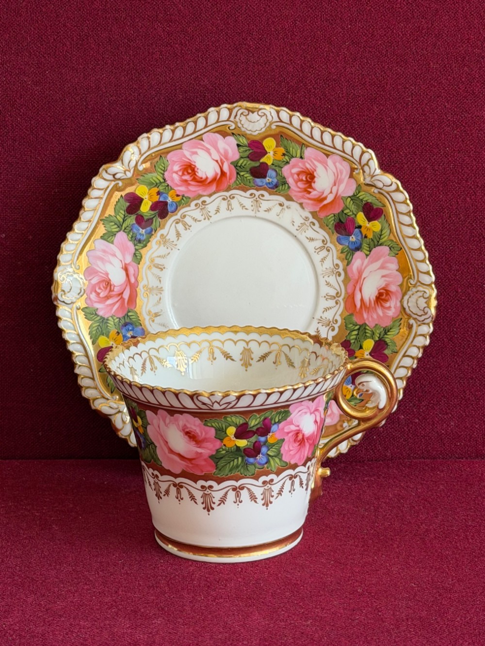 An antique Regency Chamberlain Worcester porcelain trio featuring hand-painted pink roses, pansies, rich gilded borders, and eagle-head handle terminals. View III