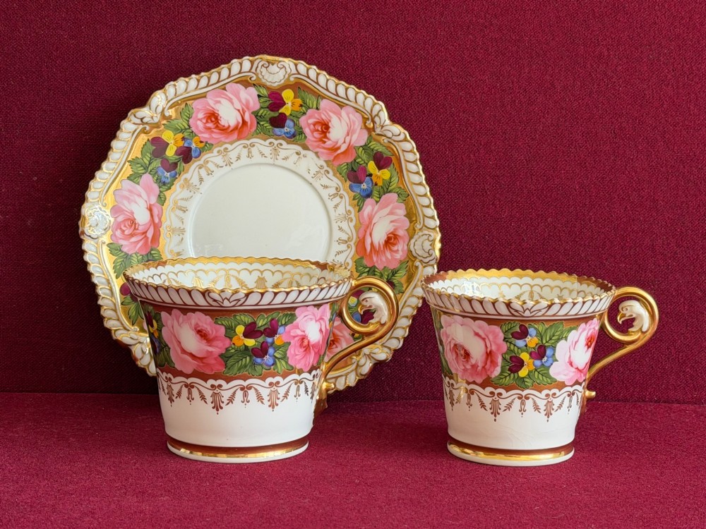 An antique Regency Chamberlain Worcester porcelain trio featuring hand-painted pink roses, pansies, rich gilded borders, and eagle-head handle terminals. View IV